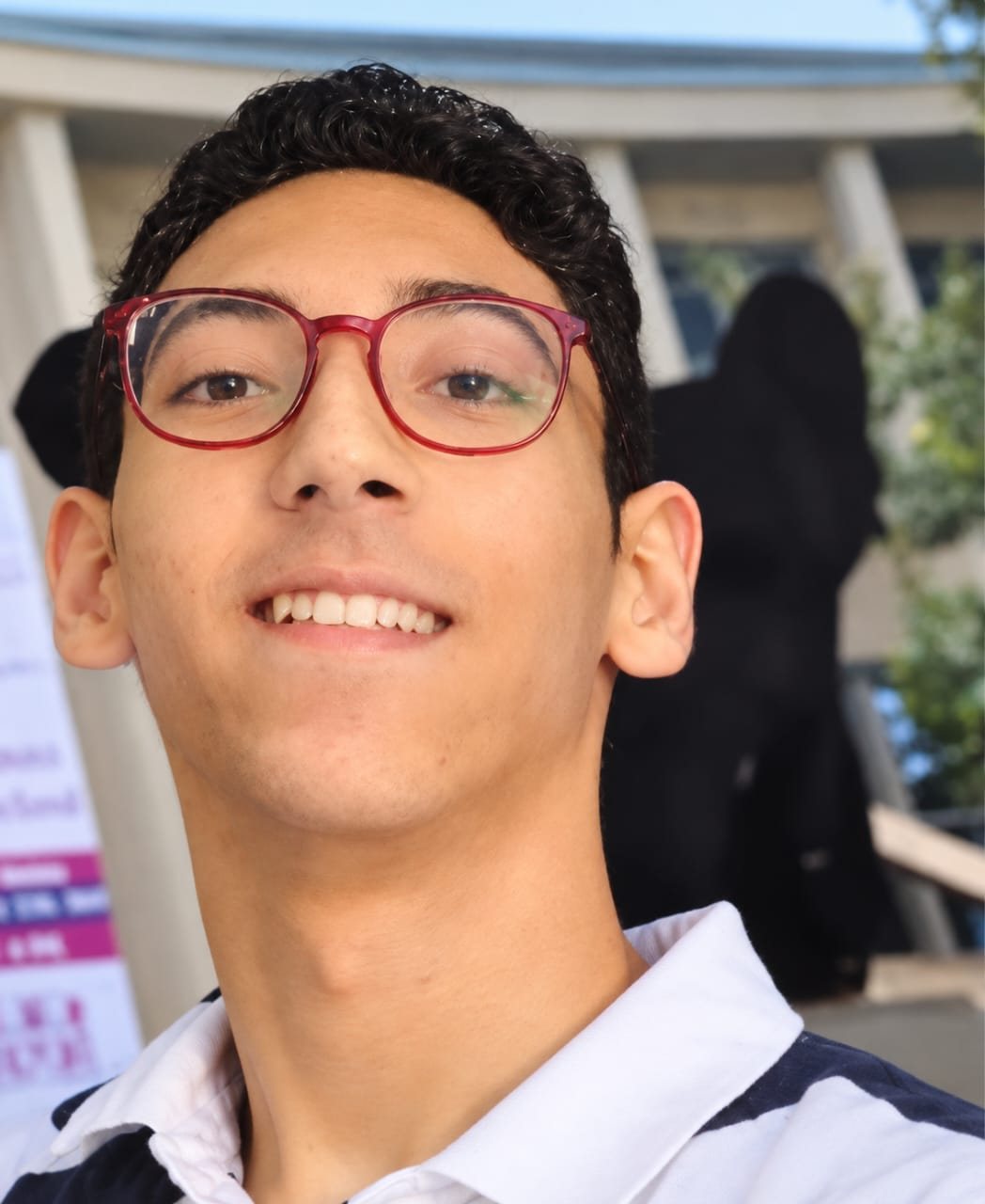 A smiling young man with red glasses.
