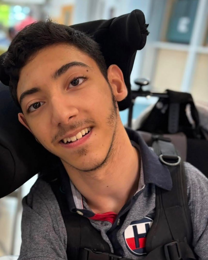 A smiling young man in his wheelchair.