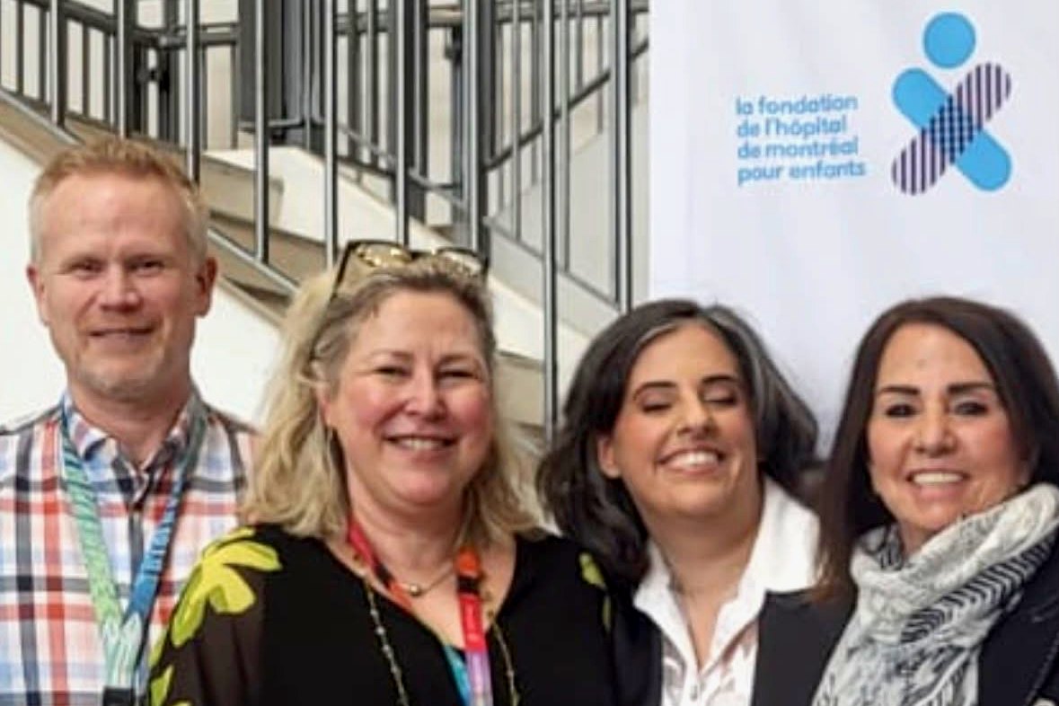 Caline Saleh with three people in front of a Montreal Children’s Hospital Foundation banner.